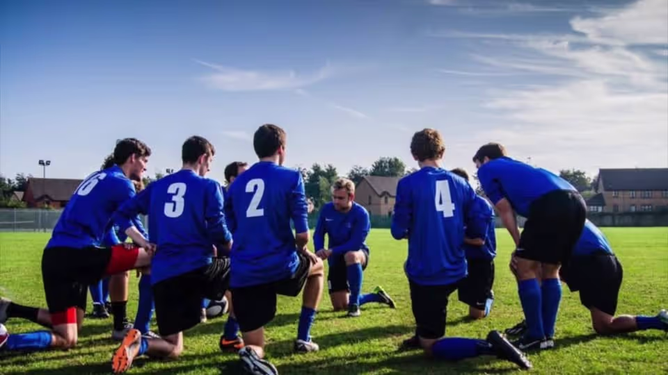 soccerteam kneeling for teamtalk on the pitch